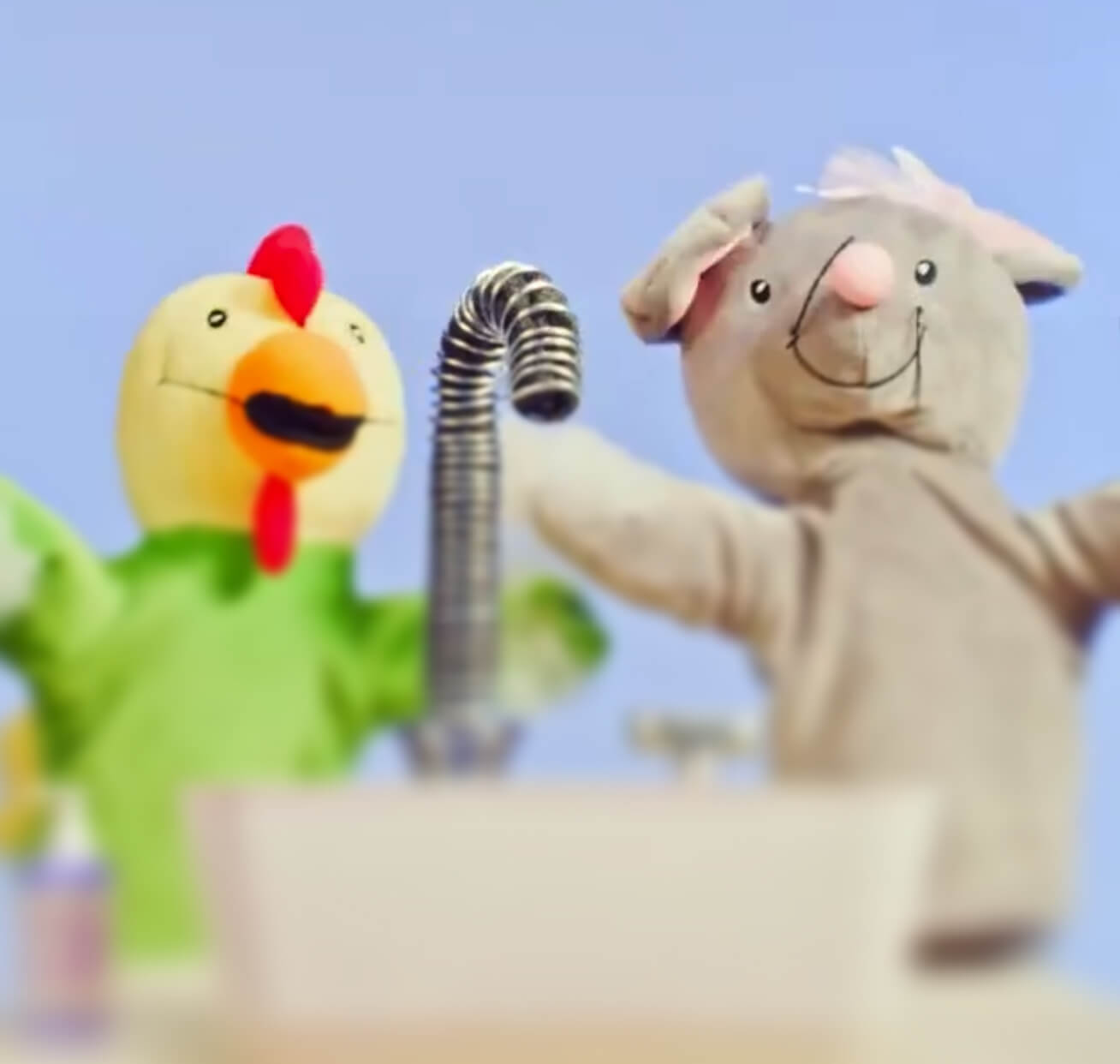 Two puppets behind a sink faucet